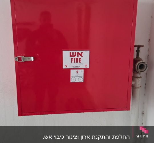 ארון כיבוי אש אדום עם צינור מים בצד